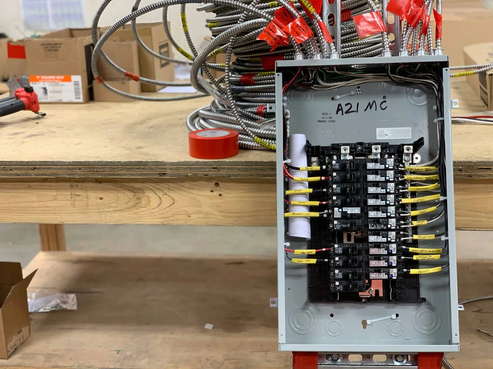 A new electrical panel with yellow-tagged wires on a workbench before installation